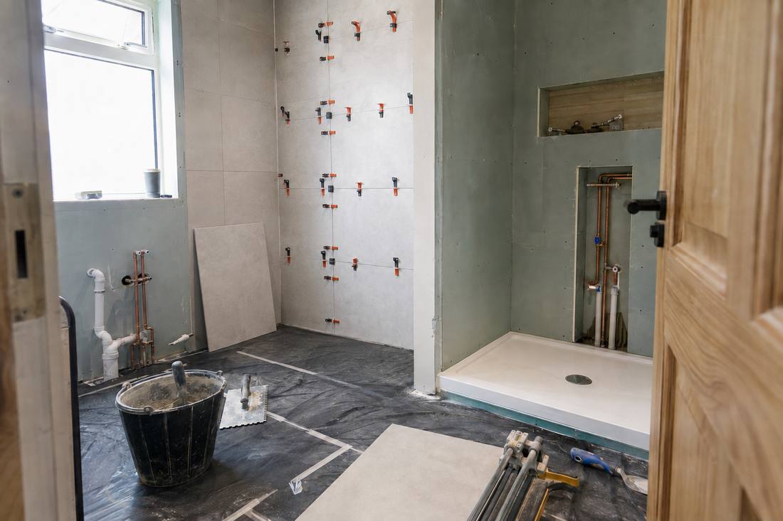 Bathroom renovation mid-build — large-format tiling up, first fix plumbing in